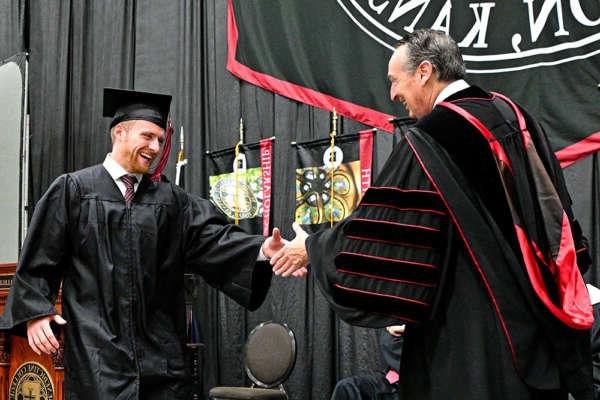 A graduate shakes hands with President Stephen Minnis during Commencement